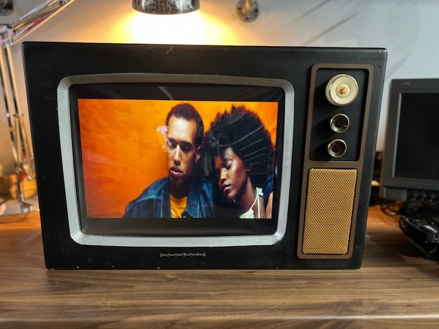 Black retro television with rotary controls for hire playing video