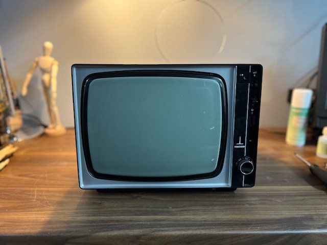 Black 1980s portable CRT television for hire with side speaker grille