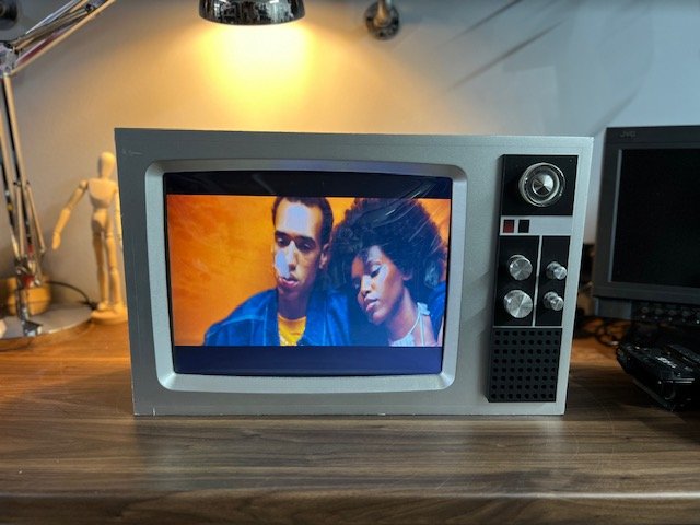 Silver retro TV with side speaker playing a music video to hire